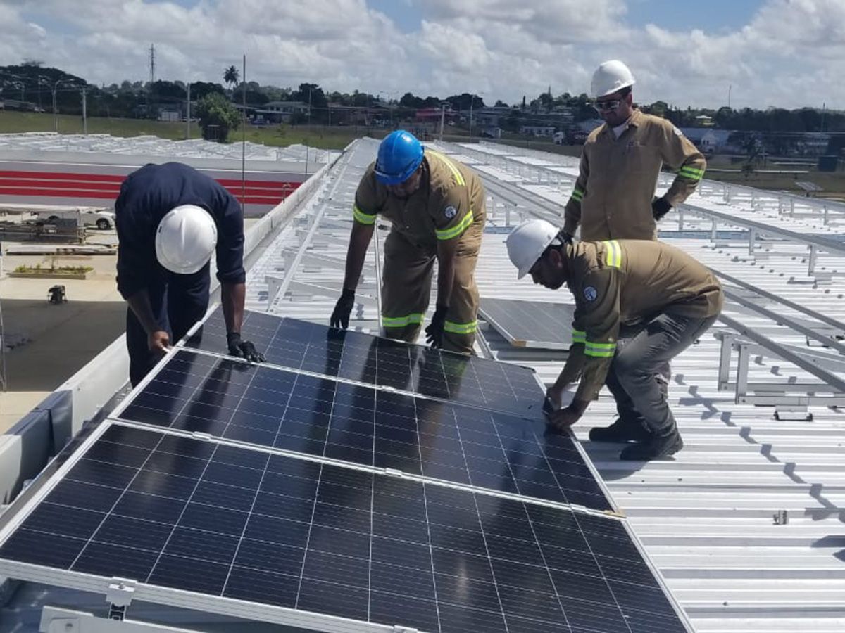 BELEC crew setting a solar panel on a metal roof