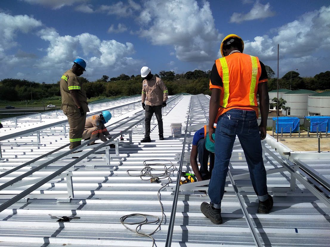 Crew setting out aluminium racking rails on a white metal roof