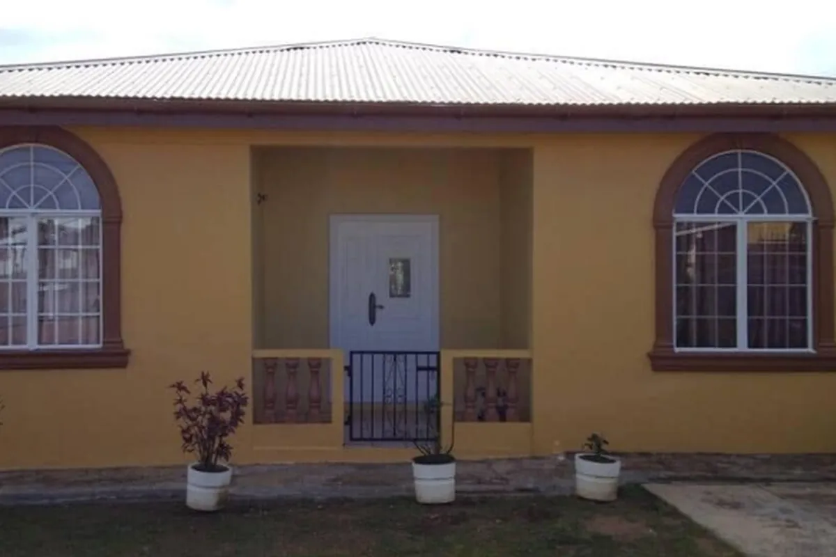 After: Finished bungalow front in yellow with brown arches