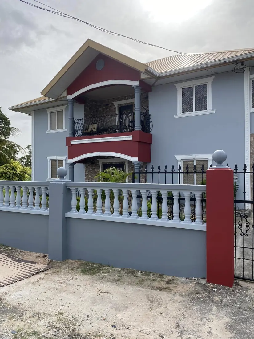 Two-storey house in grey with red balcony and pillars