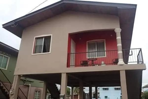 Stilted house in taupe with a red balcony