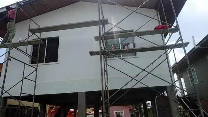 Crew on scaffolding painting a raised house