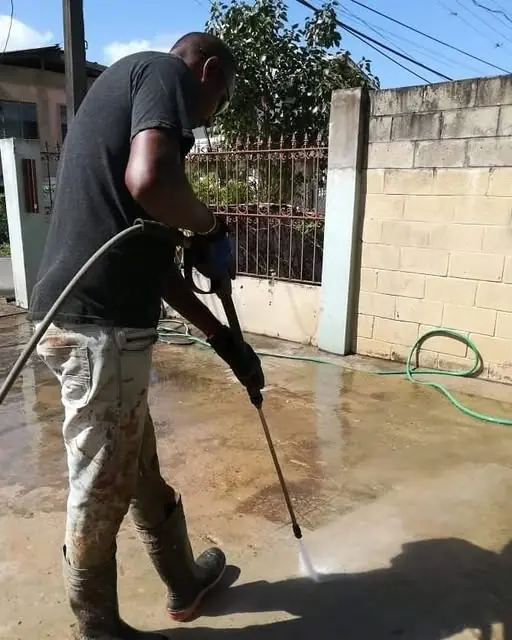 Crew member pressure washing a concrete yard